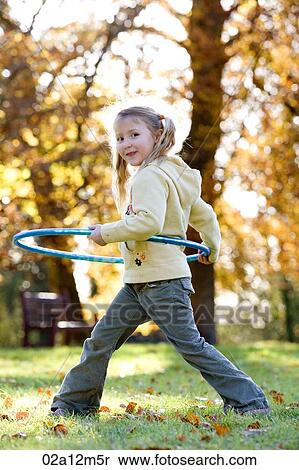 Stock Photography - Girl playing with a plastic hoop in a park. Fotosearch