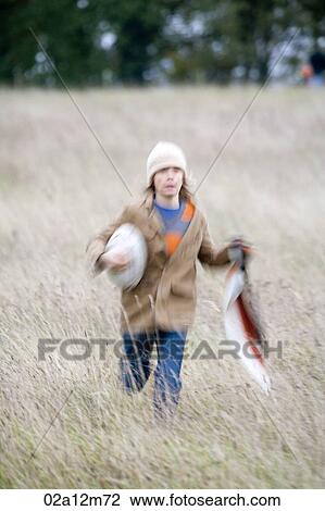 Girl running in a field with a rugby ball View Large Photo Image Stock Image - Girl running in a field with a rugby ball. Fotosearch