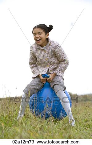 Stock Image - Girl sitting on a hoppity horse. Fotosearch
