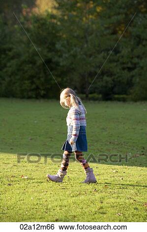 Girl walking in the grass View Large Photo Image Stock Photograph - Girl walking in the grass. Fotosearch