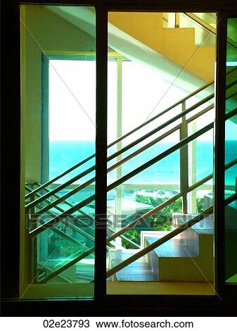 Stock Image - Glass stairwell with windows looking out onto ocean. Fotosearch