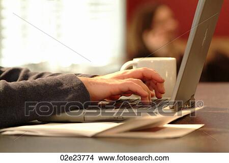 Man paying bills online while at home in kitchen. View Large Photo Image Picture - Man paying bills online while at home in kitchen.. Fotosearch