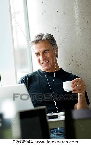 Middle-aged man listening to music in urban cafe. View Large Photo Image Picture - Middle-aged man listening to music in urban cafe.. Fotosearch