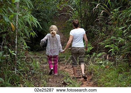 Stock Photo - Mother and daughter holding hands walking through the rainforest. . Fotosearch