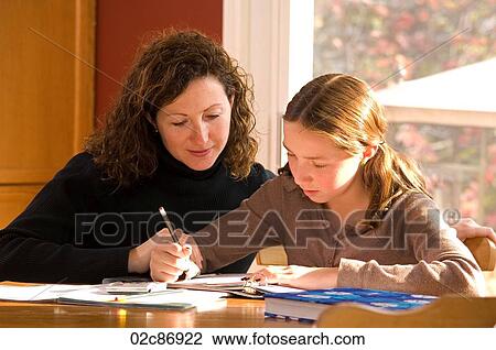 Stock Image - Mother helping her daughter with her school homework.. Fotosearch