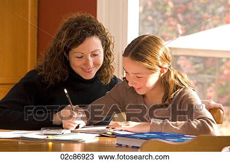 Stock Image - Mother helping her daughter with her school homework.. Fotosearch