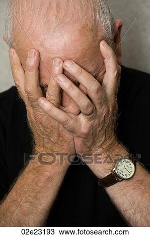 Stock Image - Old man covering face with hands in despair.. Fotosearch