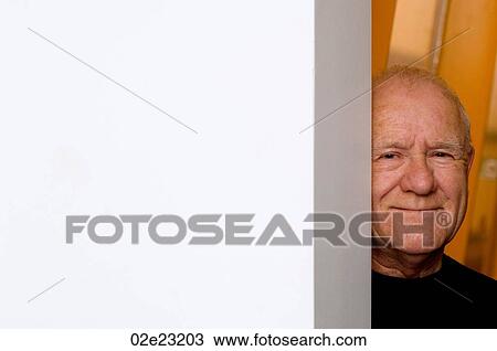 Stock Image - Old man peeking around corner of wall.. Fotosearch