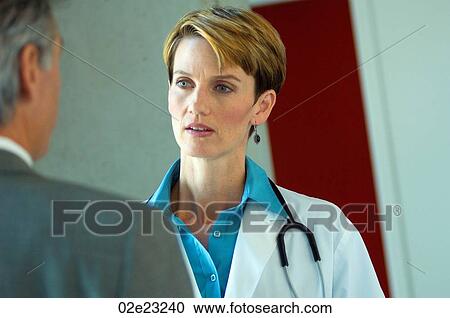 Stock Image - Patient consulting with female doctor.. Fotosearch