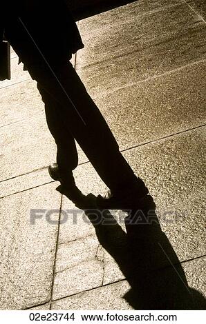 Person and their shadow walking away. View Large Photo Image Picture - Person and their shadow walking away.. Fotosearch