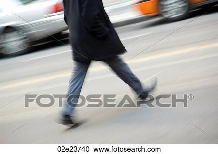 Stock Image - Person walking quickly across busy road.. Fotosearch