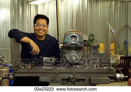 Stock Image - Portrait of Asian man in machine shop.. Fotosearch