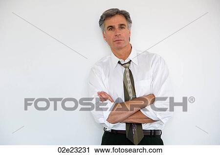 Stock Image - Portrait of businessman with sleeves rolled up.. Fotosearch