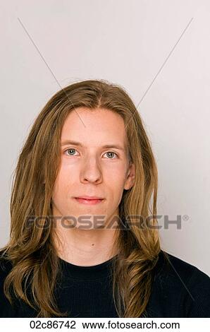 Stock Image - Portrait of young man with long hair.. Fotosearch