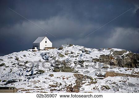 Stock Photo - Small house perched on top of snow covered mountain. Fotosearch