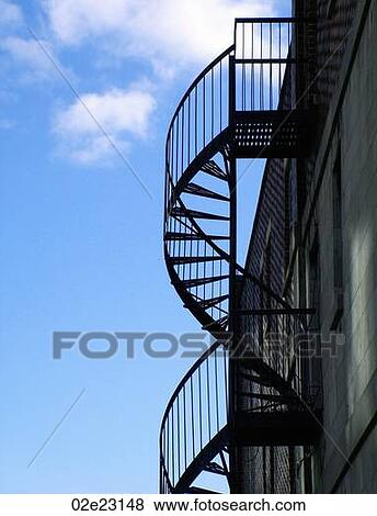 Spiraling fire escape with blue sky background View Large Photo Image Stock Photo - Spiraling fire escape with blue sky background. Fotosearch