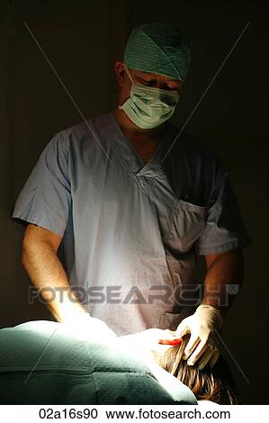 Stock Image - Surgeon examining patients head. Fotosearch