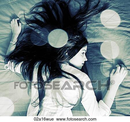 Stock Image - Teenage girl lies on bed. Fotosearch