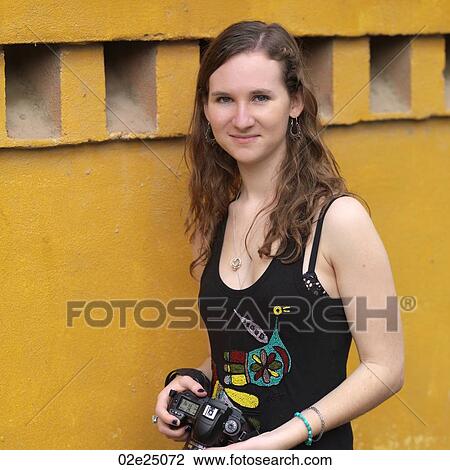 Stock Image - Teenage girl smiling holding a camera. . Fotosearch