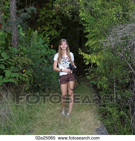 Teenage girl walking in the rain forest holding a camera. View Large Photo Image Stock Photography - Teenage girl walking in the rain forest holding a camera. . Fotosearch