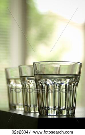 Three clear glasses lined up on a counter top. View Large Photo Image Stock Photo - Three clear glasses lined up on a counter top.. Fotosearch