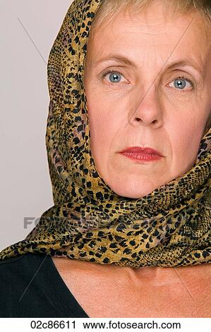 Stock Image - Tight face shot of serious mature woman wearing head scarf.. Fotosearch