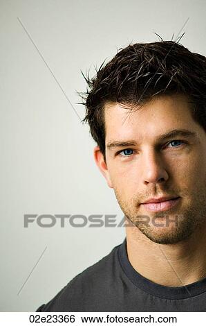 Stock Photograph - Tightly cropped face shot of a young man looking into camera.. Fotosearch