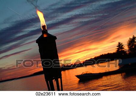 Tiki torch in-front of a lake. View Large Photo Image Stock Image - Tiki torch in-front of a lake.. Fotosearch