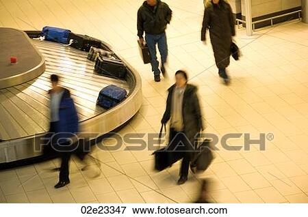 Stock Photo - Travelers collecting luggage from airport baggage carousel.. Fotosearch