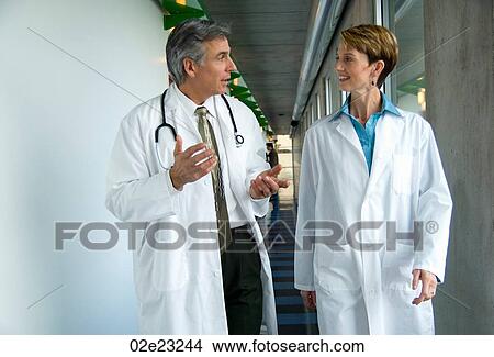 Picture - Two doctors walking down hospital corridor.. Fotosearch