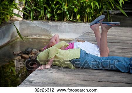 Two girls peering over the edge of a deck in Belize View Large Photo Image Stock Image - Two girls peering over the edge of a deck in Belize. Fotosearch