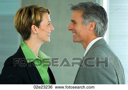 Stock Photograph - Two office colleagues smiling at each other.. Fotosearch