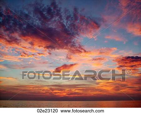 Stock Image - Vibrant sunset sky over ocean.. Fotosearch