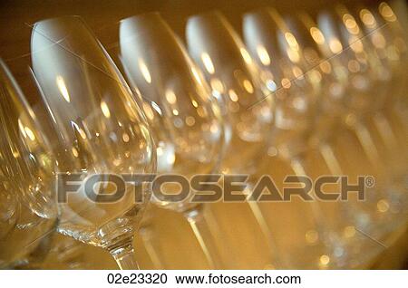 Stock Image - Wine glasses lined up on restaurant shelf.. Fotosearch