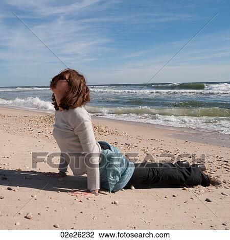 Stock Image - Woman in a yoga pose on the beach in the Hamptons. Fotosearch