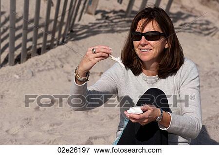 Woman looking at seashells on the beach in the Hamptons View Large Photo Image Stock Photo - Woman looking at seashells on the beach in the Hamptons. Fotosearch