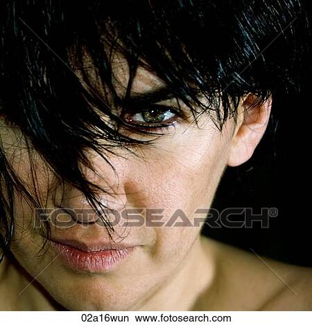 Picture - Woman looking directly at camera under black fringe. Fotosearch
