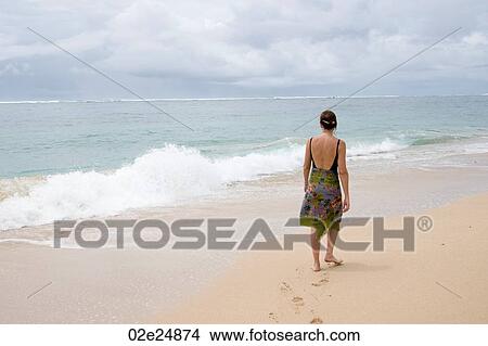 Picture - Woman walking along the beach in Bali. Fotosearch