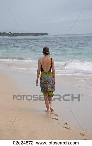 Woman walking along the beach in Bali View Large Photo Image Stock Image - Woman walking along the beach in Bali. Fotosearch