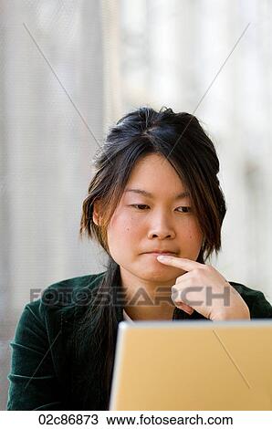 Stock Image - Young Asian university student working on laptop computer.. Fotosearch