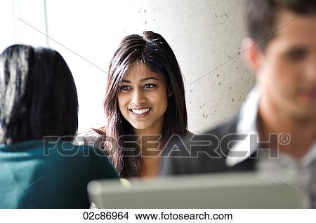 Picture - Young ethnic businesswoman chatting to colleague.. Fotosearch