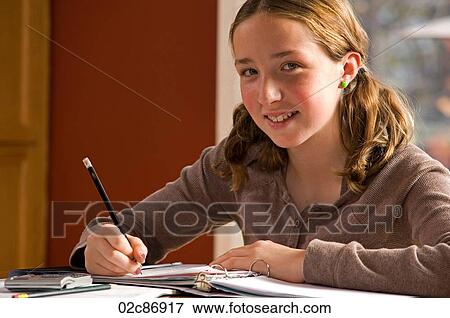 Stock Photo - Young girl doing homework at kitchen table.. Fotosearch