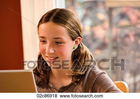 Stock Photo - Young girl doing homework on wireless laptop computer at home.. Fotosearch