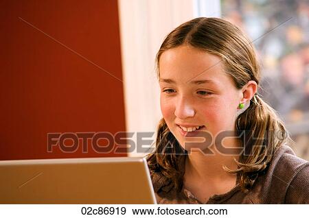 Stock Photo - Young girl doing homework on wireless laptop computer at home.. Fotosearch