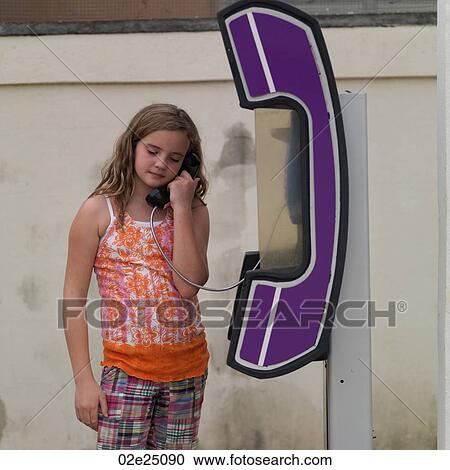 Stock Image - Young girl on the phone at a telephone booth. . Fotosearch
