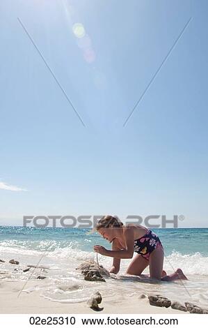 Stock Image - Young girl playing in the sand on Belizean Isle in Belize. Fotosearch