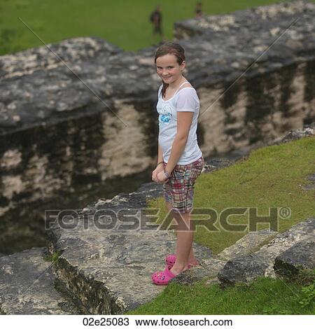 Stock Image - Young girl standing on rocks. . Fotosearch