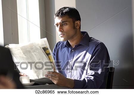 Young man reading a newspaper in a cafe. View Large Photo Image Stock Photography - Young man reading a newspaper in a cafe.. Fotosearch