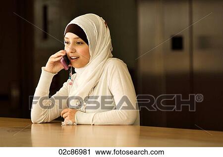 Stock Image - Young Muslim woman talking on cellphone.. Fotosearch