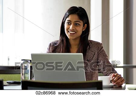 Stock Photo - Young urban business woman using a wireless laptop in a hotspot internet cafe.. Fotosearch